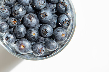 Close-up of blueberries in a transparent bowl, on white background.Fresh raw organic farm blueberry in a cup.