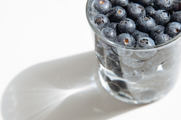Crockery with juicy and fresh blueberries on white table.Close up portrait of fresh blueberries in a glass bowl on white background