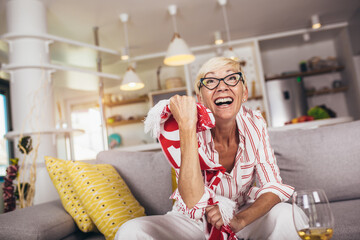 Elderly woman emotionally watching soccer on tv and celebrating victory at home.