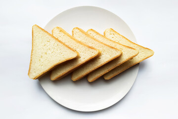 five triangular slices of bread on a white round plate on a light background closeup. pointer right  top view