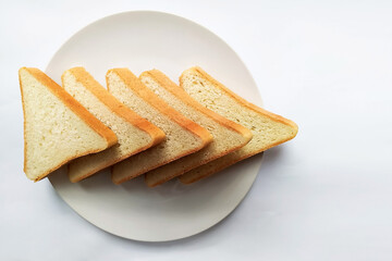 five triangular slices of bread pointing right on a white round plate on a light background closeup top view