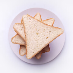 triangular slices of bread on a white round plate on a light background top view closeup