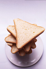 a few triangular slices of bread on a white round plate on a light background closeup top view 