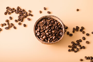 black arabica coffee beans, aromatic in a coconut dish, sprinkled beans on the table, light background, close-up, top view