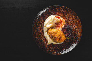 burger with mashed potatoes in white on black wooden background
