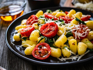 Gnocchi with tomato, spinach and parmesan  on wooden table
