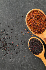 Superfood quinoa seeds, red, black on a gray background in wooden spoons. Close-up, empty space for text