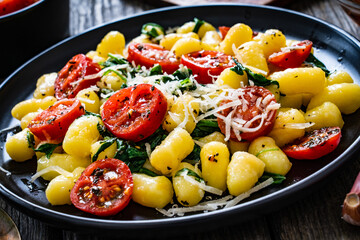 Gnocchi with tomato, spinach and parmesan  on wooden table
