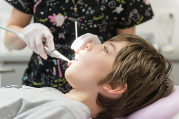 Dentist examining young boy's teeth in clinic