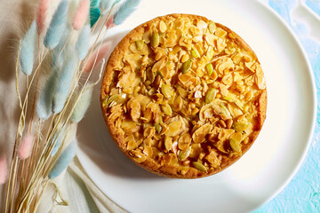 Apple or pear pie, tart with caramel nuts on blue table with sunlight