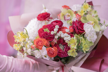 A lush beautiful bouquet of red, orange, yellow, white cute delicate flowers of different sizes and colors, roses, green leaves. Romance.