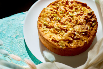 Apple or pear pie, tart with caramel nuts on blue table with sunlight