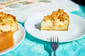 Piece of apple or pear pie, tart with caramel nuts on blue table with sunlight