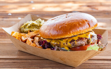 Fresh tasty burger and french fries on wooden table