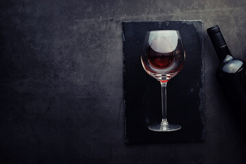 Wine glass and black wine bottle. Nuts cheese and tomatoes for snack.