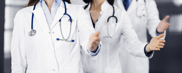 Group of doctors are standing as a team while offering their helping hands for shaking hand or saving people's life. Medicine concept during Coronavirus pandemic. Covid-2019