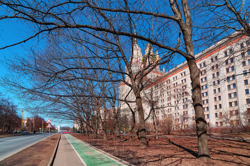 Panoramic wide angle view of spring sunset campus of Moscow university with blue sky and naked tree branches