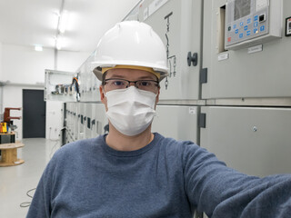 Fototapeta na wymiar Young engineer working in electrical substation wearing a face mask.