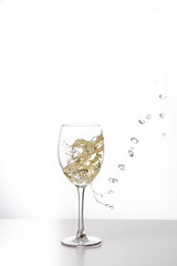 Weißwein im Weinglas mit weinspritzer aus dem glas