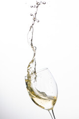 Weißwein im Weinglas mit weinspritzer aus dem glas