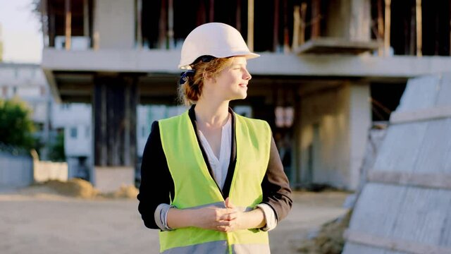 Beautiful blonde hair lady engineer with a large smile at construction site with a white helmet he looking straight to the camera and smiling large