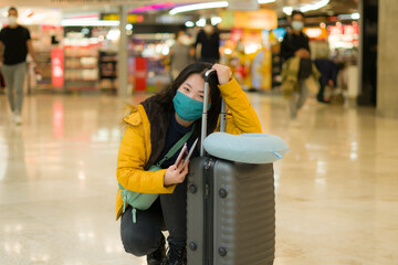 Asian woman flying in covid19 times - lifestyle portrait of young happy and pretty Korean girl in face mask waiting on airport lounge ready for holiday trip