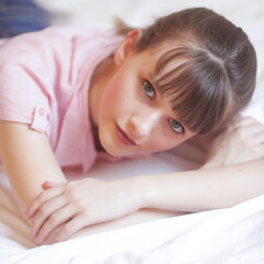 Obraz na płótnie Canvas Portrait beauté d'une adolescente aux yeux bleu allongée sur un lit