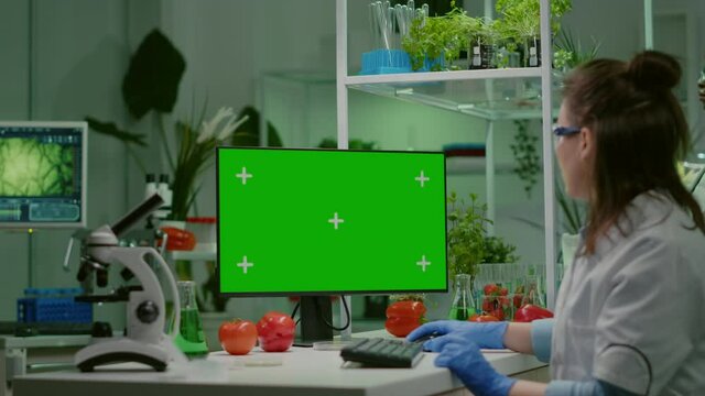 Pharmaceutical researcher looking at computer with mock up green screen chroma key with isolated display typing on keyboard medical expertise. Biologist working in microbiology laboratory