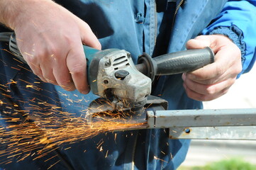 the master cuts a metal bar with a grinder