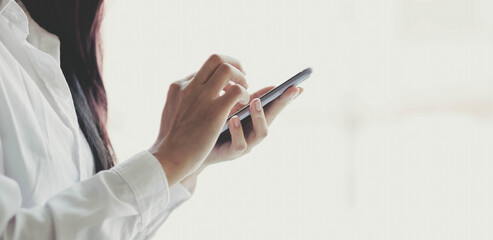 close up hand of businesswoman using mobile phone at office building, online business concept.
