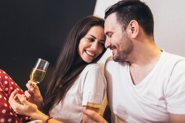 Happy young couple drinking champagne in bed