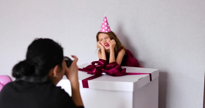 Woman photographer take photo of little birthday smiling girl in studio or at home, professional shoots at the Birthday party.