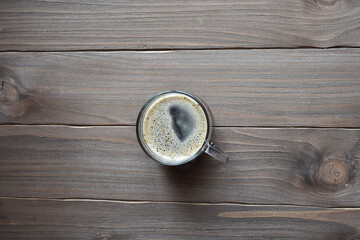 transparent cup of coffee with foam, on a wooden table glass