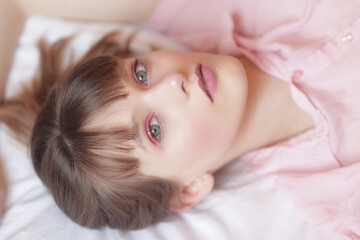 Obraz na płótnie Canvas Portrait beauté d'une adolescente aux yeux bleu allongée sur un lit