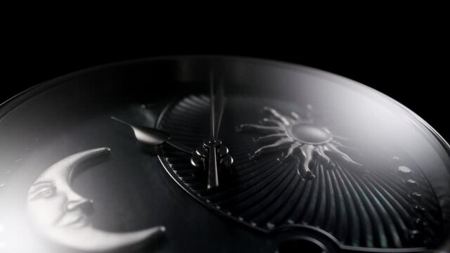 Silver second arrow running on nacrous clockface of rotating swiss made watch with moon and sun. Closeup of metallic details and ribbed pattern on black background