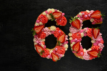 Beautiful cake in the shape of number 66. Modern trendy design. Springtime decoration. Copy space. Low key. Unusual bright dessert. Birthday card.