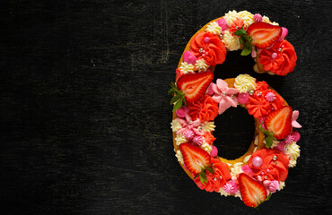 Beautiful cake in the shape of number 6. Modern trendy design. Springtime decoration. Copy space. Low key. Unusual bright dessert. Birthday card.