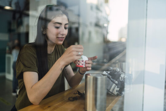Chica joven guapa tomando helado en la barra de una cafeteria