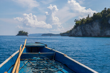 rudimentary blue boat in the middle of the sea in front of a small island, travel concept