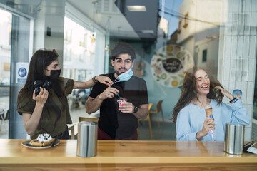 Amigos chicos y chicas tomando helado en la barra interior de una heladeria