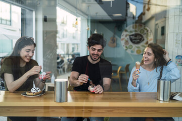 Amigos chicos y chicas tomando helado en la barra interior de una heladeria