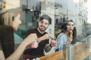 Amigos chicos y chicas tomando helado en la barra interior de una heladeria