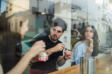 Amigos chicos y chicas tomando helado en la barra interior de una heladeria