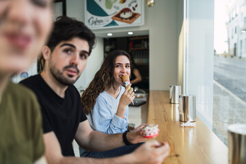 Amigos chicos y chicas tomando helado en la barra interior de una heladeria