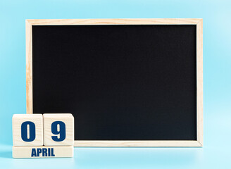 April 9th. Day 9 of month, Cube calendar with date, empty frame on light blue background. Place for...