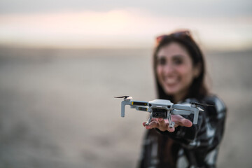 Chica joven sujetando drone en la playa al tardecer