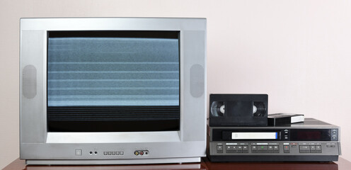 Fototapeta premium Old silver vintage TV with noise and interference on the screen and VCR on the background of the wallpaper. 1980s, 1990s, 1970s.