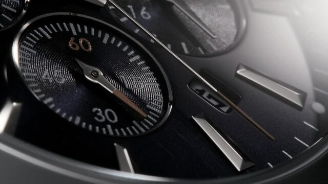 Silver and red second arrow running on the dark blue clockface of luxury swiss watch with chronograph and metallic details. Closeup with zoom-in effect 