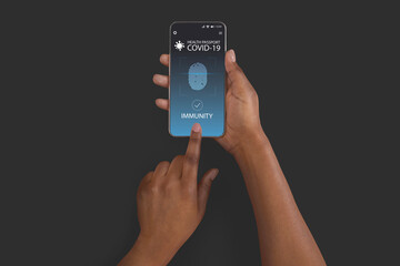 Black lady using smartphone with digital immune e-passport for covid-19