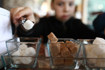 Boy taking piece of sugar with tongs